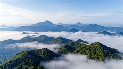 A beautiful landscape of mountain peaks emerging from a sea of clouds under a clear blue sky. The mountains are covered in lush green vegetation.