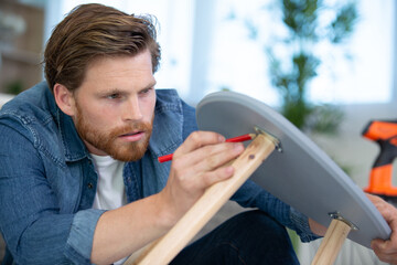 carpenter measuring chair part with electric callipers in workshop