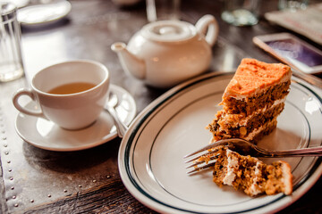 Tea time in a café with carrot cake on a wooden table