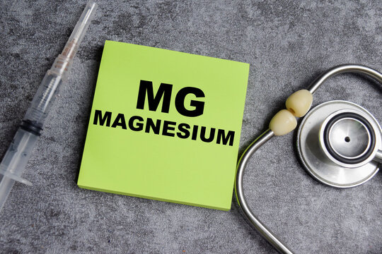 Concept of MG - magnesium write on sticky notes isolated on Wooden Table.