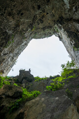 Silhouette of Person Standing on Rock Viewed Through Eroded Limestone Cave Arch in China