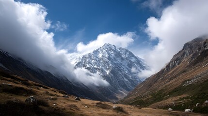 Majestic snow covered mountain peak in a valley with dramatic clouds