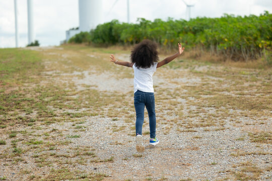 Child runing in Wind Farm. Windmill. environmental renewable clean energy. Wind power generation. Nature Outdoor activitie. African American black girl