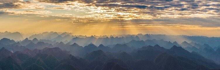 Golden Sunbeams Breaking Through Dramatic Clouds Over Endless Karst Mountains in Qibainong Guangxi China