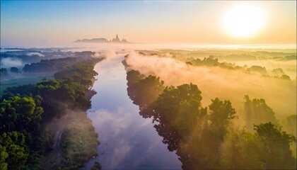 Aerial view of a river winding through a lush landscape with trees and fog, bathed in the warm light of sunrise.