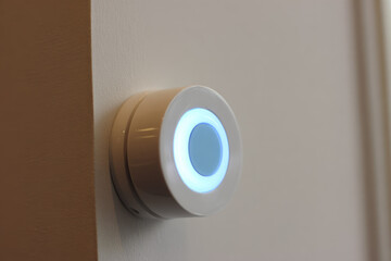 Smart home device with glowing blue light on wall, resembling iris for eye scanner security system, modern technology for access control and safety