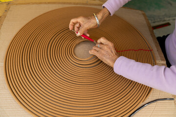 Artisan Hands Carefully Shaping Large Traditional Spiral Coil Incense with Red Thread Binding
