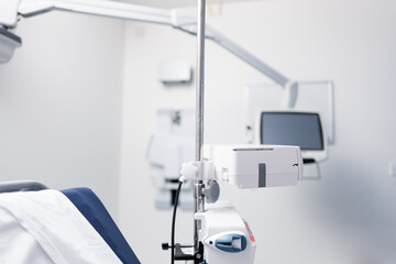 Shallow focus of a generic IV pump seen on a vertical adjustable stand by a patients bed in a typical NHS hospital.