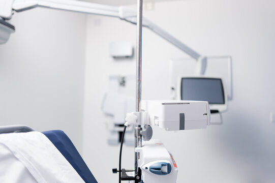 Shallow focus of a generic IV pump seen on a vertical adjustable stand by a patients bed in a typical NHS hospital.