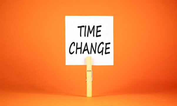 Time change symbol. Concept word Time change on beautiful white paper. Beautiful wooden clothespin. Beautiful orange background. Business time change concept. Copy space.