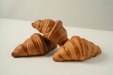 Three golden brown croissants piled on a white background isolated on white background