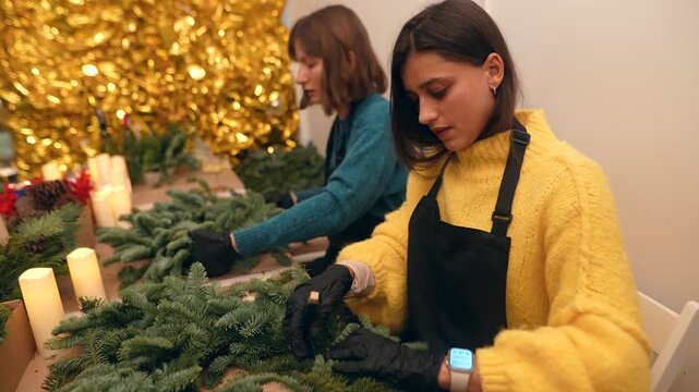 Skilled craftsmen assembling holiday greenery with candles and tools