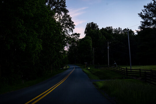 Countryside rural paved road in Lyndhurst, Virginia at evening dark night sunset with fence at Longstaff lane and Reeds gap road in mountains