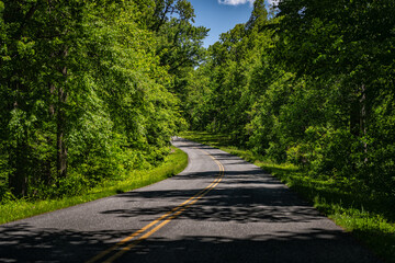 Car point of view driving on empty winding road in Blue Ridge mountains parkway forest green trees in Virginia summer
