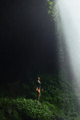 Obraz premium Sexy Woman in Swimsuit Standing Under Dramatic Jungle Waterfall Light