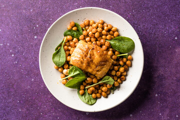 Pan-seared cod served with chickpeas and fresh spinach on a white plate