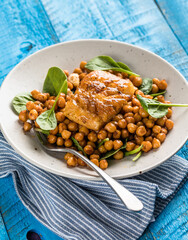 Pan-seared cod served with chickpeas and fresh spinach on a white plate