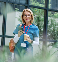 Senior mature woman or a nurse or a doctor during office hours walking down the street and using...