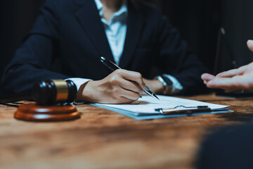Legal professional in business suit signing a contract or agreement document on a clipboard during a consultation about judicial matters