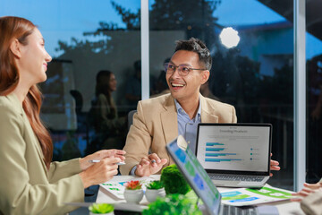 Business team discussing market trends and growth, collaborating on a project with laptops and documents in a modern office