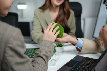 Business professionals hands gently holding a vivid green moss ball during an office meeting, symbolizing environmental growth and ESG