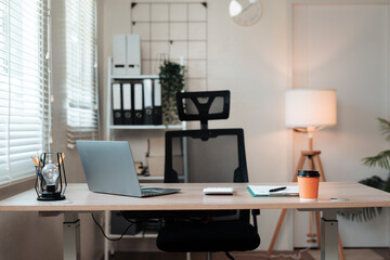 Empty home office with a modern standing desk, open laptop, and organizational items for remote work or studying
