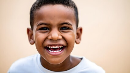 Naklejka premium portrait of a laughing 6–7 year old boy wearing a simple T-shirt, standing against a soft light background