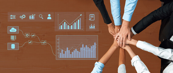 A collaborative team gathering with hands joined on a wooden table, showcasing data visualization, charts, and graphs for effective business analysis and strategy. Trope