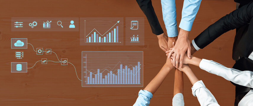 A collaborative team gathering with hands joined on a wooden table, showcasing data visualization, charts, and graphs for effective business analysis and strategy. Trope - Powered by Adobe