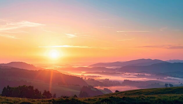 A beautiful sunrise over a mountain range with fog in the valley below. The sky is a mix of orange, yellow, and blue, creating a warm and peaceful atmosphere.