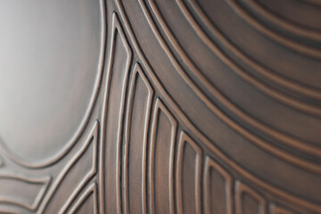 Abstract curved pattern on a brown background. Convex lines. The glare of light on the surface of the background. Abstract brown background with curved parallel lines and shadows.
