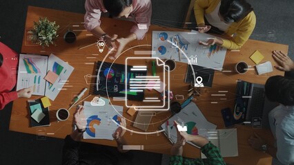 A diverse group of professionals collaboratively discusses business strategies while analyzing data charts and reports on a shared workspace. Raster