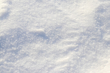 Detailed texture of white, clean and fresh snow with bright, sparkling crystals illuminated by sunlight creating a frosty, cold, clean and holiday winter background