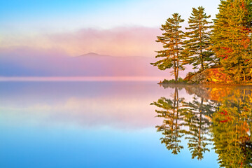 autumn mountain lake Barnum Pond in the Adirondacks of New York state reflecting with colorful morning fog at daybreak