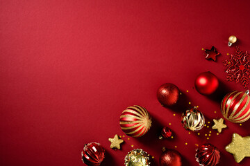 Christmas flat lay composition. Top view red and stiped golden baubles, stars, snowflakes on rich red background.