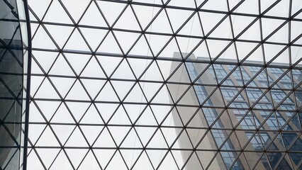 Glass ceiling grid reflecting modern office building facade