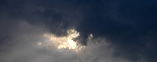 Dramatic landscape of a cloudy sky as a ray of sunlight breaks through dark gray storm clouds