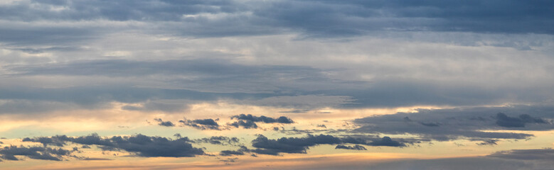 panoramic gray sky background with subtle pink-yellow hues on the horizon and multiple layers of clouds: from light transparent to dark and fluffy