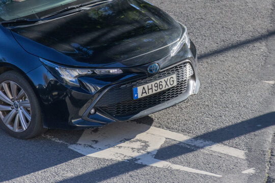 Black toyota corolla hybrid car driving on asphalt road