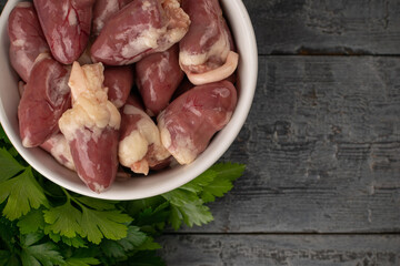 Raw Chicken Hearts in Bowl with Parsley on Rustic Wooden Surface