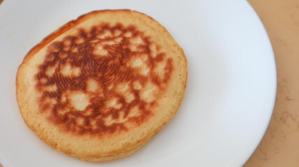 Close up of a piece of imperfect homemade pancake on a white plate 