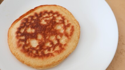 Close up of a piece of imperfect homemade pancake on a white plate 