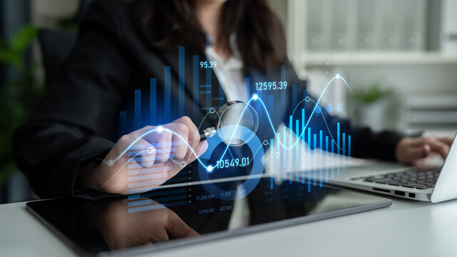 A businesswoman reviews financial data on a tablet while examining interactive graphs and charts, illustrating growth trends and market analysis in a modern office. Scalp - Powered by Adobe