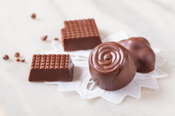 Small milk chocolates on a white lace doily and a white background. 