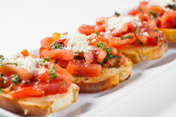 Clise-up bruschetta with tomato and basil on a white plate.