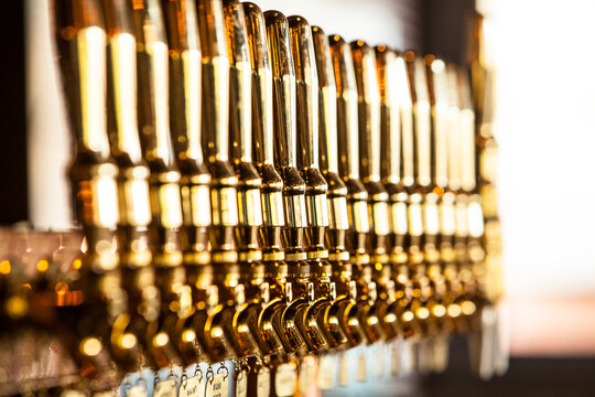 Row of several bar taps in a bar with a gold color. - Powered by Adobe