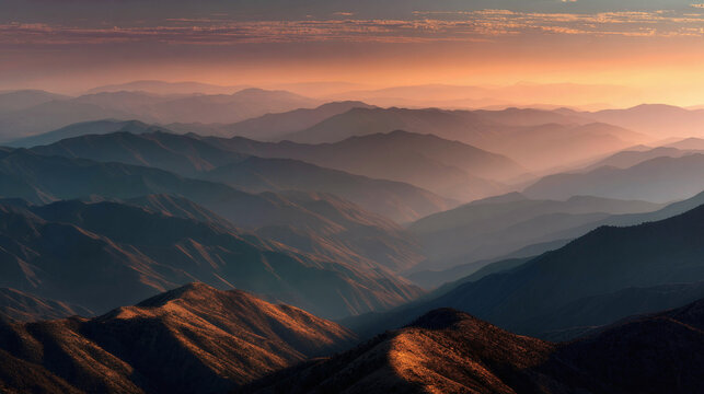 A breathtaking view of layered mountains at sunset, with a golden and hazy atmosphere