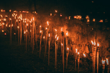 Flickering torches illuminate a stone wall at night, creating a warm and inviting atmosphere,...