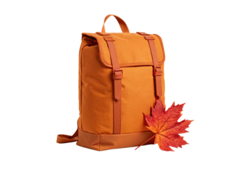 Orange fabric backpack with fall maple leaves beside it, isolated on a transparent background
