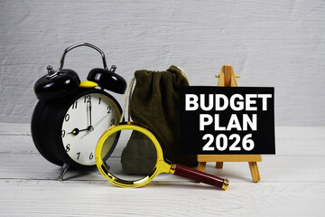Budget Plan 2026 text with alarm clock and magnifying glass on wooden background